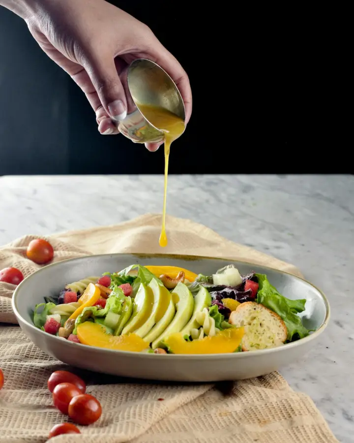 Molho sendo servido sobre salada com abacate